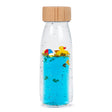A clear sensory bottle with blue liquid, containing a floating rubber duck, beach ball, and decorative glitter.