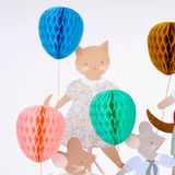 Detailed view of animal cake toppers, focusing on a cat in a floral dress with honeycomb balloons.
