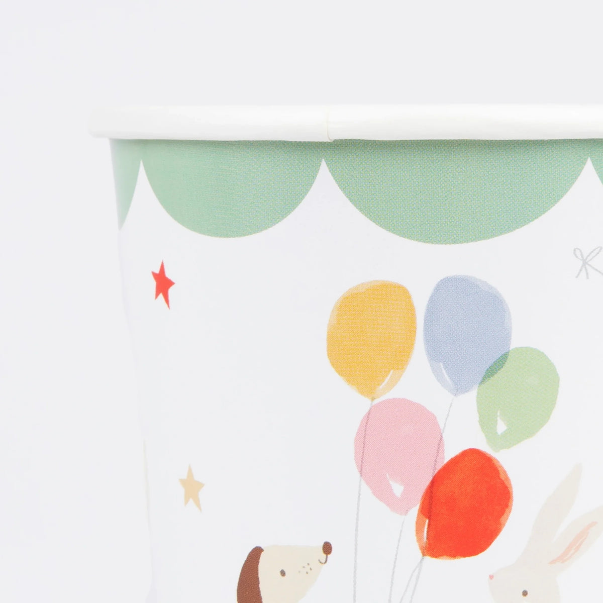 Close-up of a paper cup featuring colorful balloons, stars, and cute animal illustrations.
