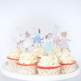 Group of frosted cupcakes displayed on a white stand, decorated with Meri Meri animal friends cupcake toppers and floral liners.