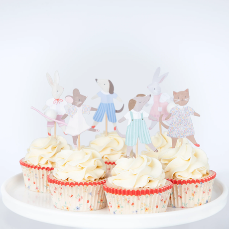 Group of frosted cupcakes displayed on a white stand, decorated with Meri Meri animal friends cupcake toppers and floral liners.
