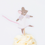 Close-up of a frosted cupcake topped with an illustrated mouse wearing a white dress with floral sleeves and a pink tail.