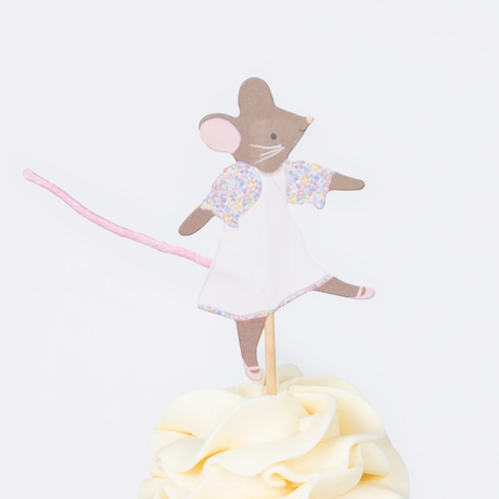 Close-up of a frosted cupcake topped with an illustrated mouse wearing a white dress with floral sleeves and a pink tail.