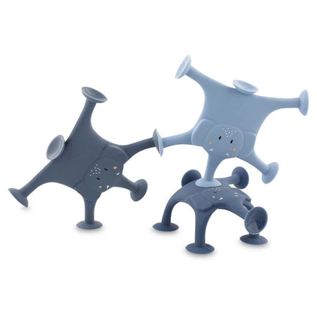 Three playful, blue-toned, elephant-shaped toys with suction cup limbs are stacked creatively. They convey a whimsical, fun, and playful mood.