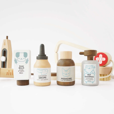 Wooden toy pet medicine set with paw balm, ear drops, medicine bottle, and pet shampoo in a row.