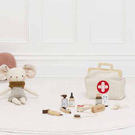 Wooden toy vet set with canvas bag and medical tools displayed on a rug next to a plush mouse.