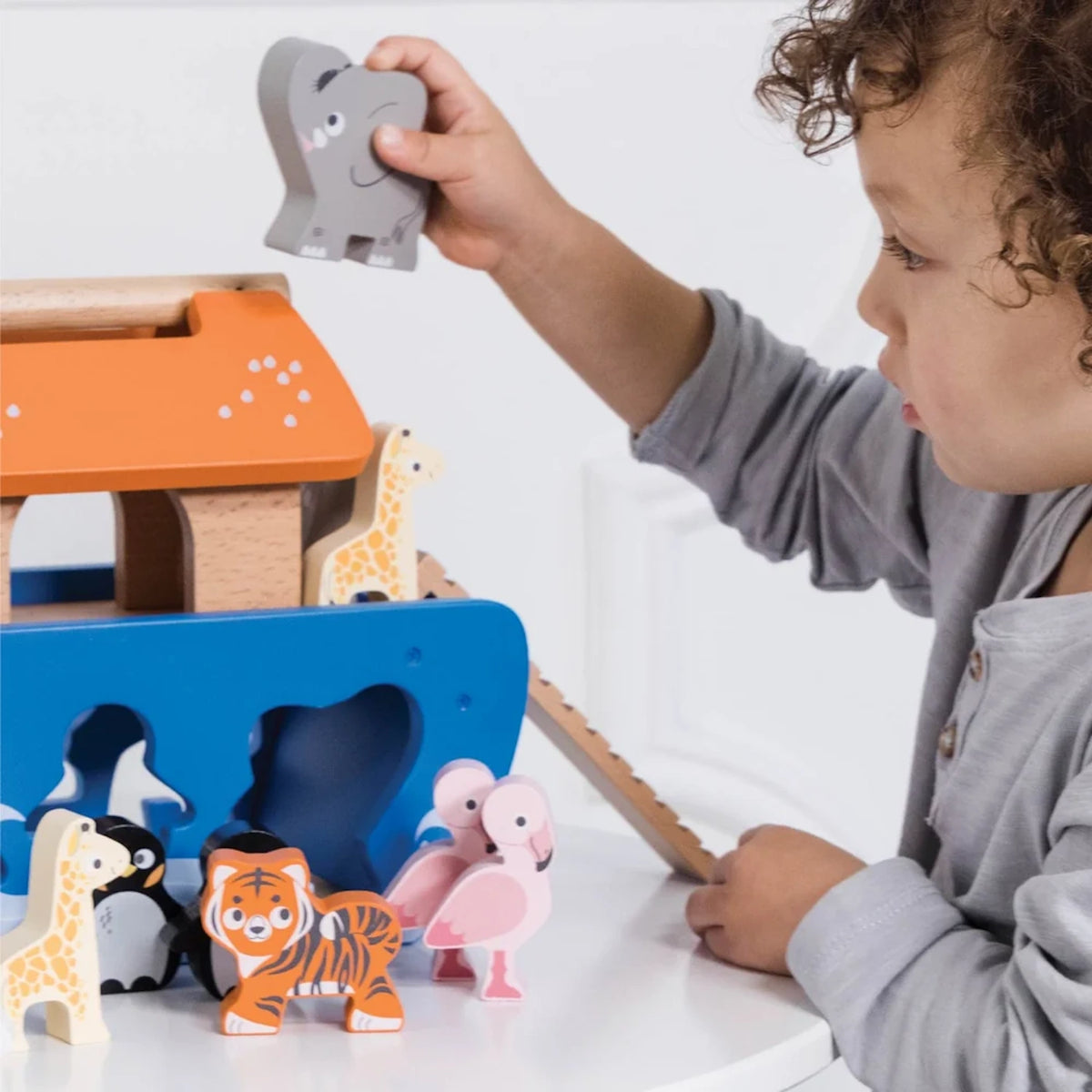 Toddler playing with the wooden Noah's Ark shape sorter and matching animal blocks.