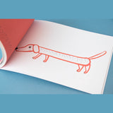 An illustration of a long, orange dachshund dog in a Londji art activity book on a blue background.