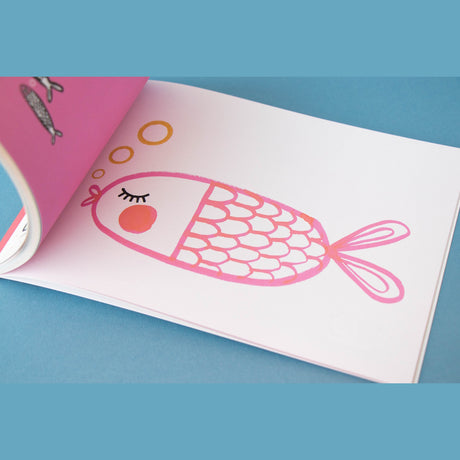 Pink illustration of a fish with scales and bubbles in a Londji art activity book on a blue background.