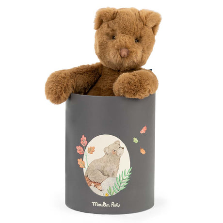 Plush brown teddy bear sitting inside a cylindrical grey gift box decorated with an illustration of a bear.