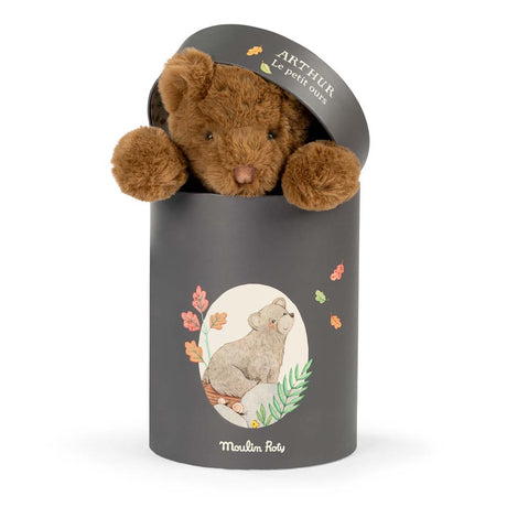 A brown plush teddy bear peeking out of a charcoal grey cylindrical gift box labeled "Arthur Le petit ours."