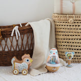 Wooden chicken pull toy and bird wobbler in a boho nursery with wicker baskets and cream baby blanket.
