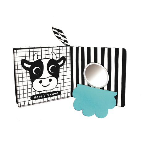 Open black-and-white cloth baby book featuring a cow page and a small circular mirror with a blue flap.