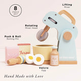 An 8-piece wooden toy baking set featuring a pastel blue lifting mixer, bowl, rolling pin, milk, Velcro eggs, and sugar and flour boxes.