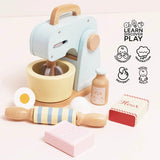 Wooden toy baking set with pastel blue mixer, bowl, rolling pin, milk bottle, egg halves, and flour/sugar boxes.