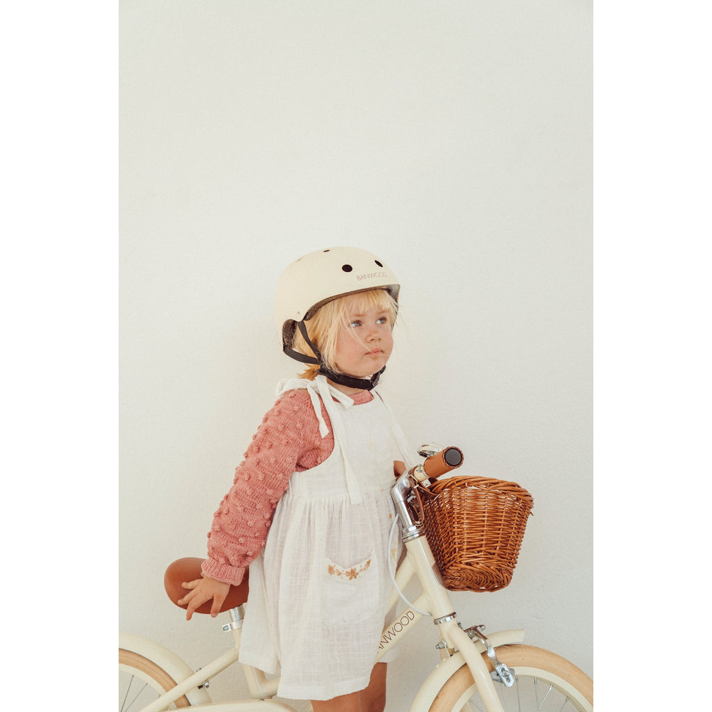 A stylish and durable kids’ bike helmet in a soft cream color, featuring an adjustable chin strap and ventilation for safety and comfort.