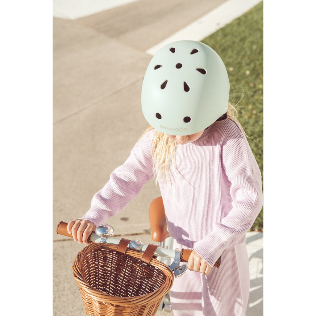 A vintage-inspired kids' bike helmet in a pale mint green shade, designed with ventilation, adjustable straps, and a secure fit for safety and comfort.