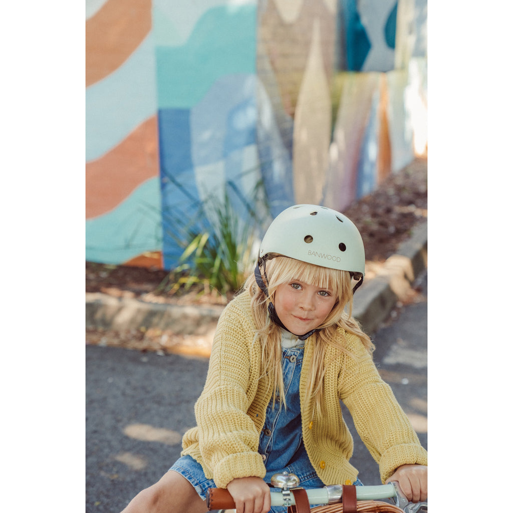 A vintage-inspired kids' bike helmet in a pale mint green shade, designed with ventilation, adjustable straps, and a secure fit for safety and comfort.