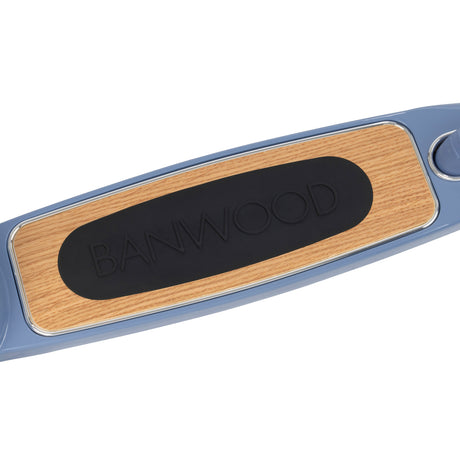 Banwood scooter blue deck close-up showing natural wood grain surface with black non-slip rubber grip pad and logo.