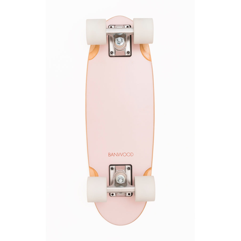 A vintage-inspired cruiser skateboard featuring a pastel pink deck, soft wheels, and a durable maple wood finish, perfect for young beginners.