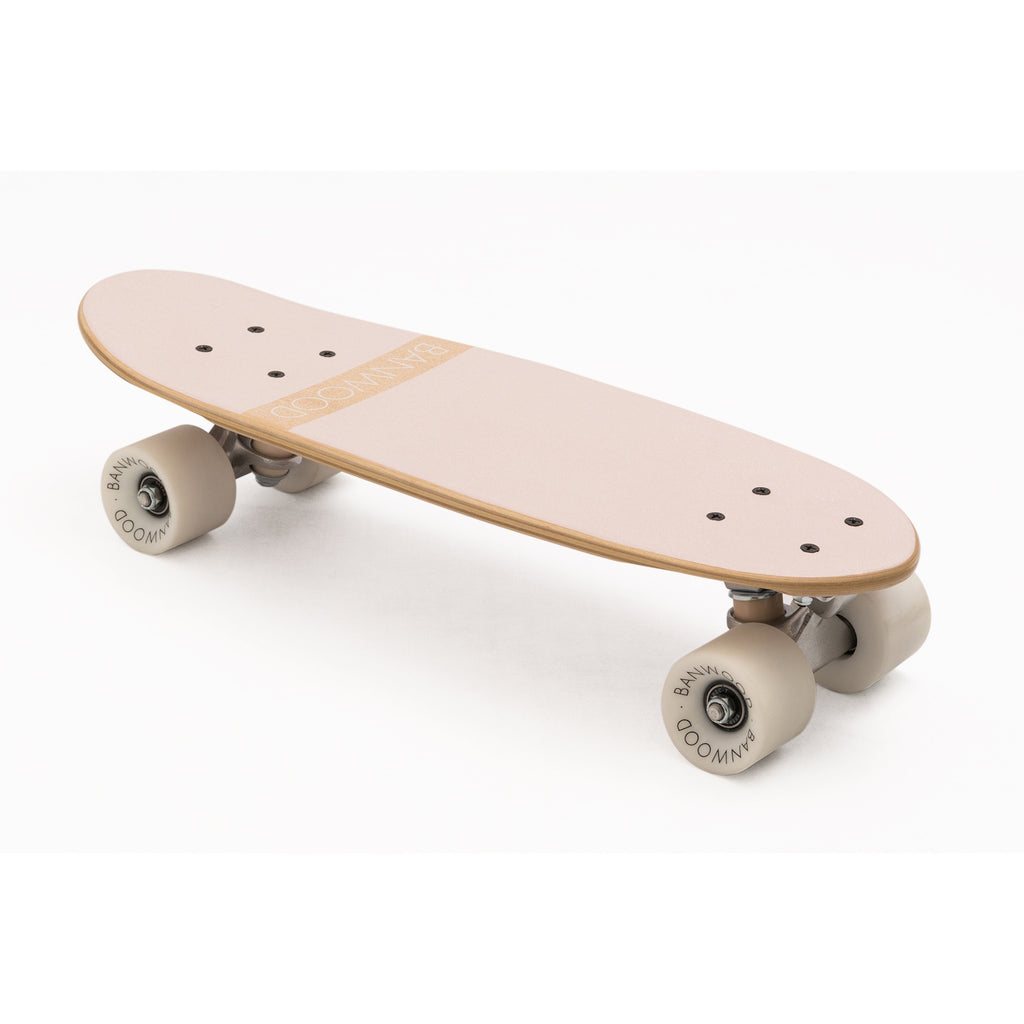 A vintage-inspired cruiser skateboard featuring a pastel pink deck, soft wheels, and a durable maple wood finish, perfect for young beginners.