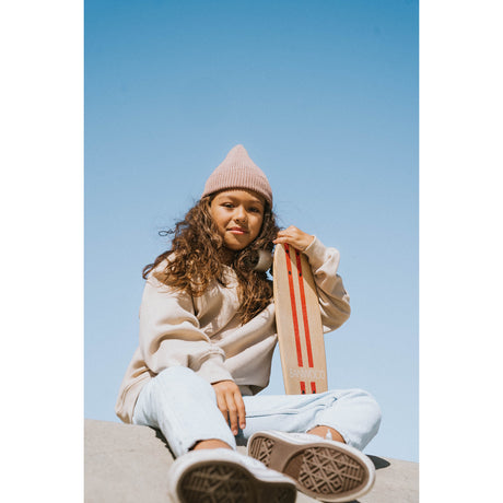 A retro-style cruiser skateboard with a bold red deck, soft wheels, and a sturdy maple wood construction, designed for smooth rides and young skaters.