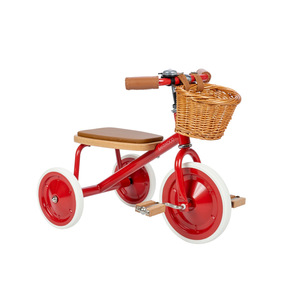 A classic children’s tricycle with a vibrant red steel frame, wooden pedals, removable push bar, and a wicker basket for timeless style and fun rides.