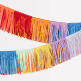 Close-up of a colorful rainbow fringe garland draped against a white background.