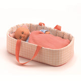 Baby doll sleeping in a pink fabric carrycot bed with matching blanket and pillow.