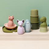 Colorful animal bath toys including a pink cat, purple mouse, blue shark, and green dinosaur on a shelf.