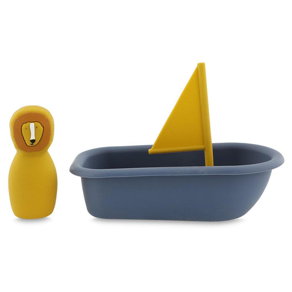 A yellow toy lion figure stands beside a blue toy boat with a yellow sail. The scene is simple, playful, and suggests a sense of adventure.