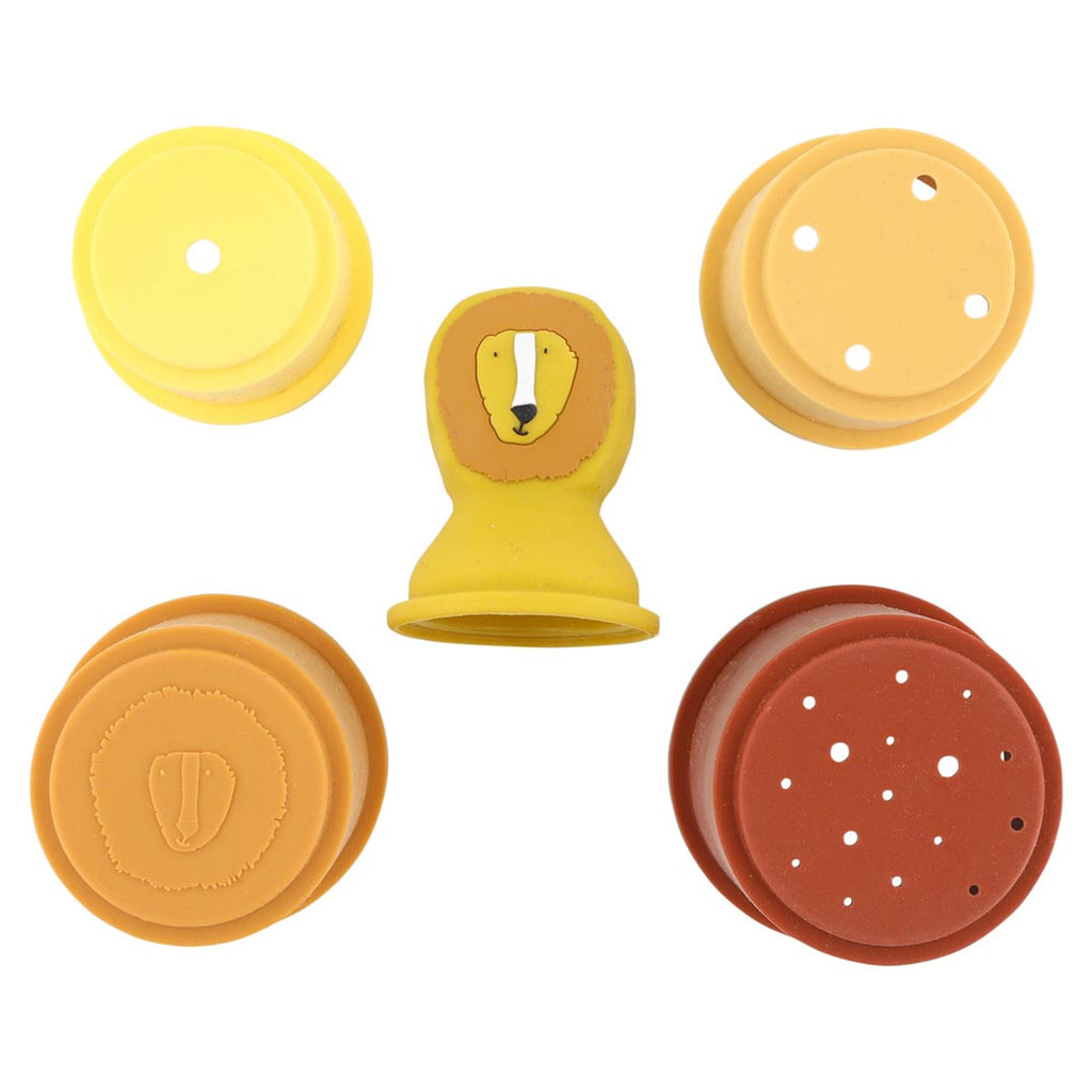Colorful silicone stamps and discs with a lion head design are arranged in a circle. The playful, cheerful colors include yellow, orange, and brown.