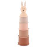Stack of five pastel-colored toy cylinders topped with a smiling rabbit head. The colors range from light pink to brown, creating a playful, gentle tone.