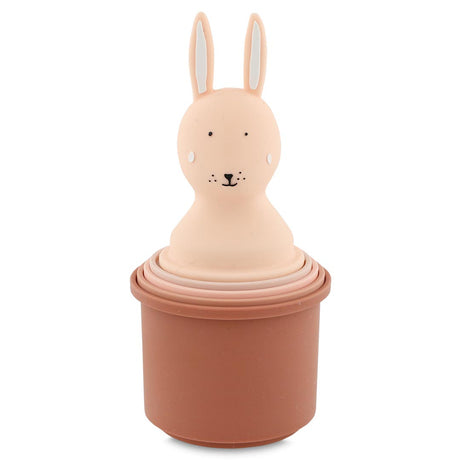 A set of pink nesting cups topped with a cute rabbit head. The rabbit has long ears, dotted eyes, and a small smile, creating a playful tone.