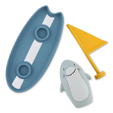 Silicone shark bath toy set with blue surfboard and yellow flag for toddlers.