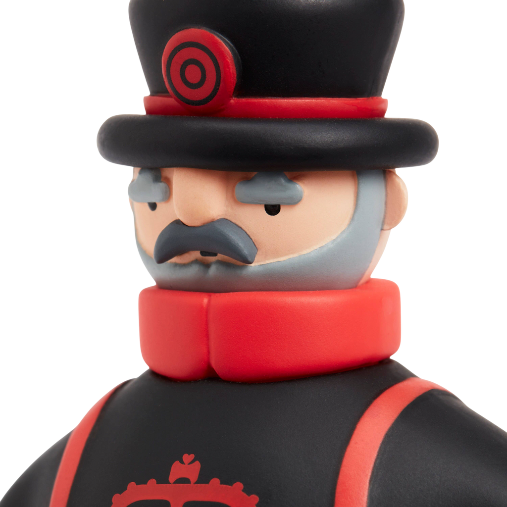 Toy figure with a serious expression, wearing a black top hat and coat with red accents, featuring a curled mustache and gray beard, on a white background.