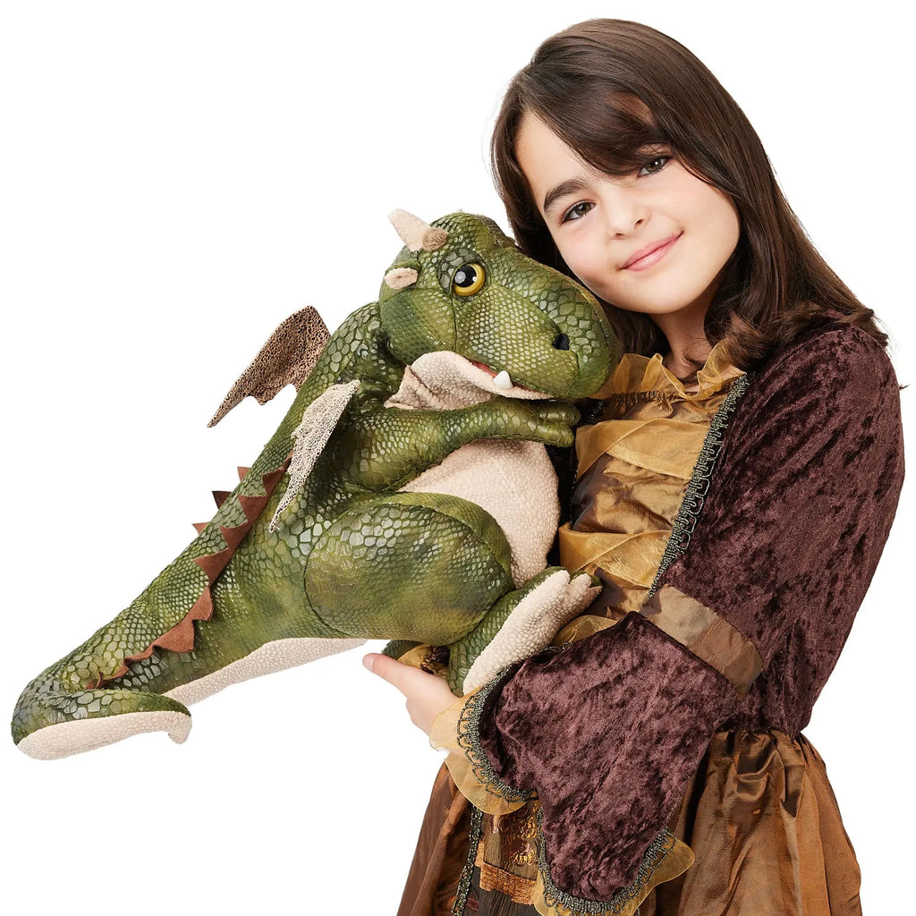 A girl in a brown velvet dress smiles while hugging a large green dragon plush toy with wings and textured scales. The scene feels warm and playful.