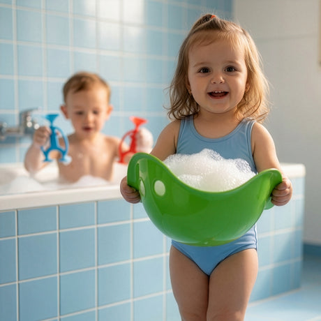 A smiling girl in a blue swimsuit holds a bubble-filled green toy, with a boy in the tub.