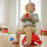 Toddler sitting on a red Bilibo chair holding a toy.