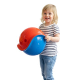Smiling toddler holding two colorful, interlocking Bilibo shells in red and blue on a white background.