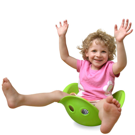 Smiling young child in a pink shirt sitting and playing in a lime green Bilibo sensory toy against a white background.