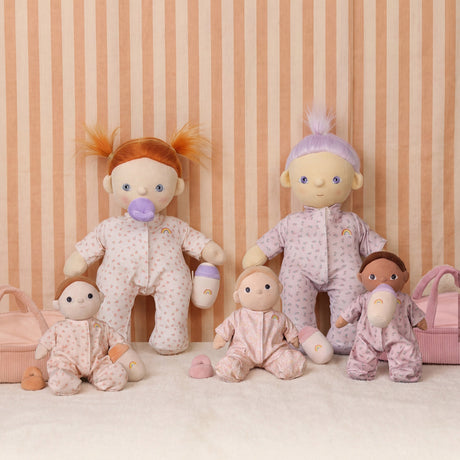Olli Ella Dinkum Dolls and Cozy Dinkums plush baby toys with bottles on a striped background.