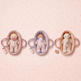 Three Olli Ella Dinky Dinkum plush baby dolls with pacifiers, lying in matching fabric bassinet carriers.