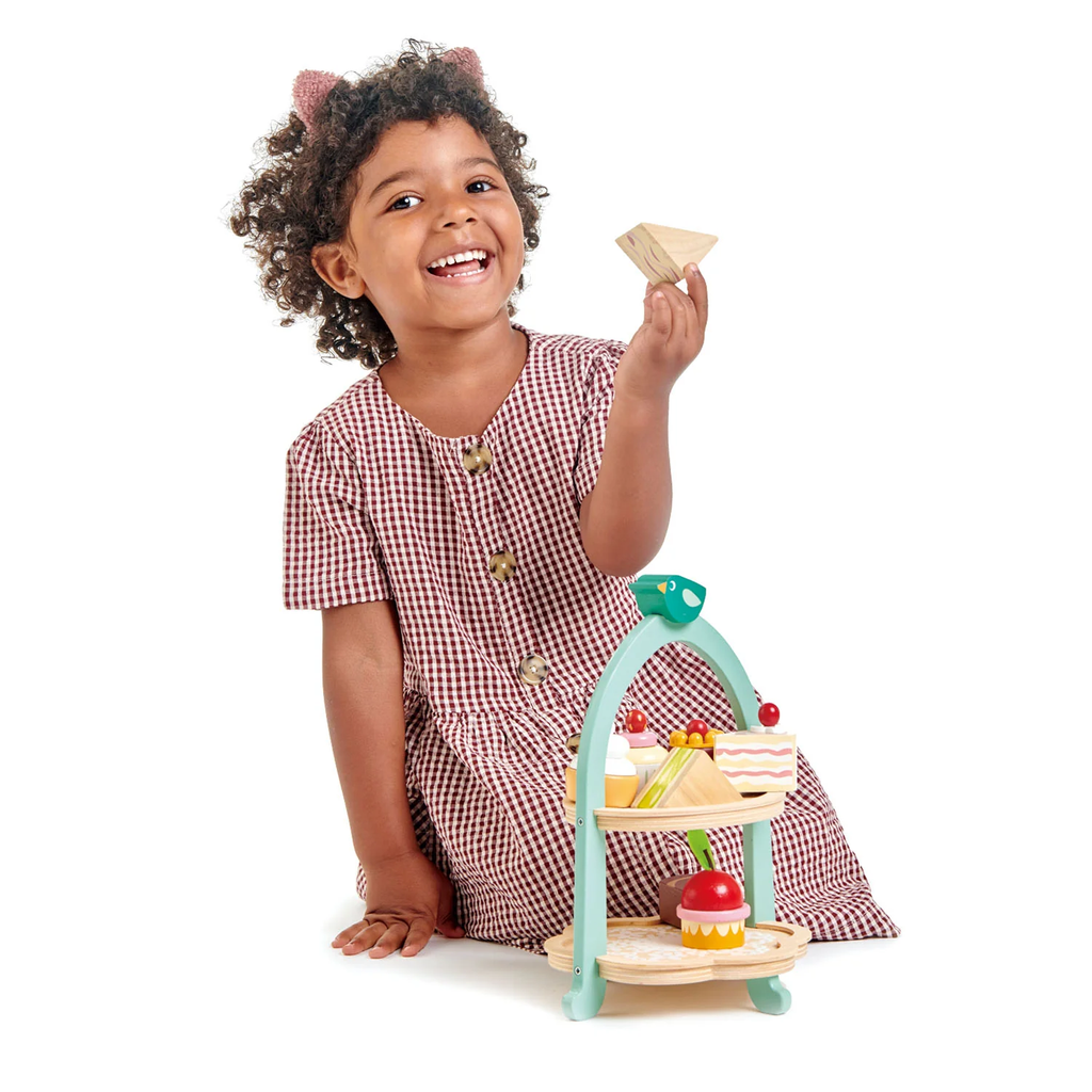 A charming wooden play set featuring a two-tiered stand with bird details, complete with toy cakes and treats for pretend tea parties.