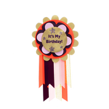 "It's My Birthday!" rosette badge with colorful layered scalloped trim and hanging ribbons.