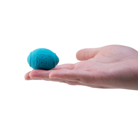 Teenie NeeDoh teal football-shaped stress ball held in a person's palm, a squishy sensory fidget toy for stress relief.