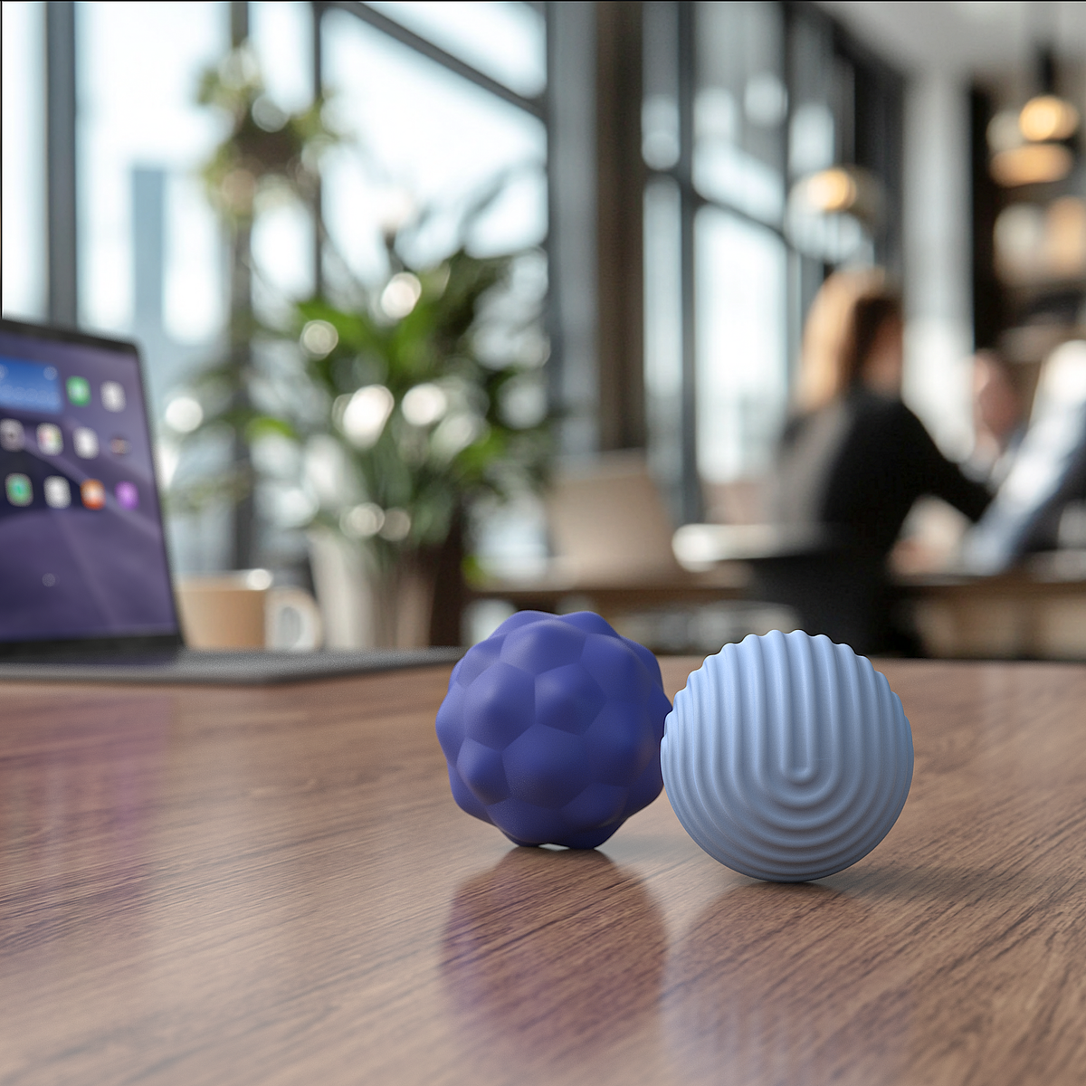 Two blue textured sensory balls on a wooden desk in a modern office setting.