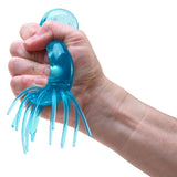A hand squeezing a blue, translucent jellyfish-shaped squishy toy with long tentacles against a white background.
