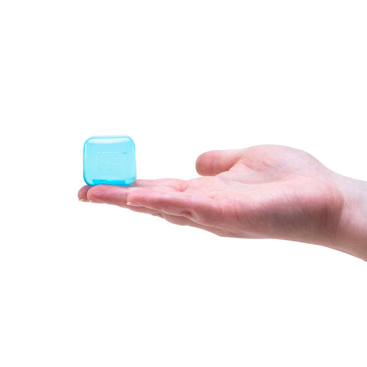 A small, translucent blue ice cube toy sitting on the fingertips of an open hand against a white background.
