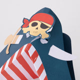 A blue paper shark craft wearing a pirate skull and crossbones emblem with a red bandana.